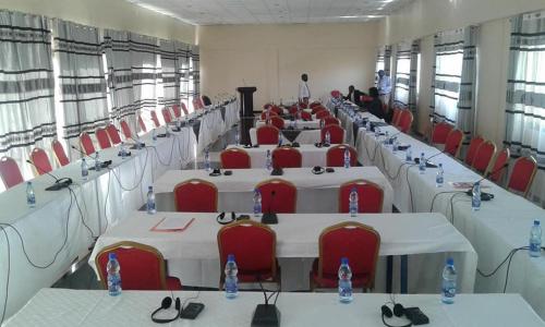 a room with rows of tables and red chairs at ARCH APARTMENTS and HOTEL in Kampala
