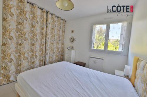 une chambre avec un lit blanc et une fenêtre dans l'établissement La Nonna, à Carry-le-Rouet