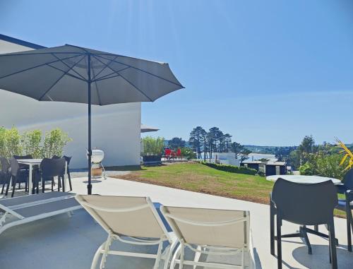 un patio con tavolo, sedie e ombrellone di La Maison des Falaises a Crozon