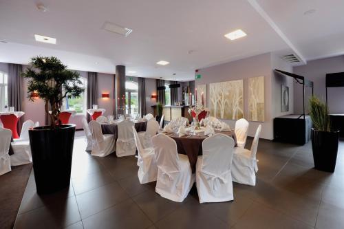 a dining room with white chairs and a table at Hotel Verviers Van der Valk in Verviers