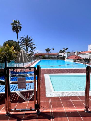 a view of a swimming pool from a balcony with two chairs at CAN HOST YUMBO - Private Terrace AA in San Bartolomé de Tirajana