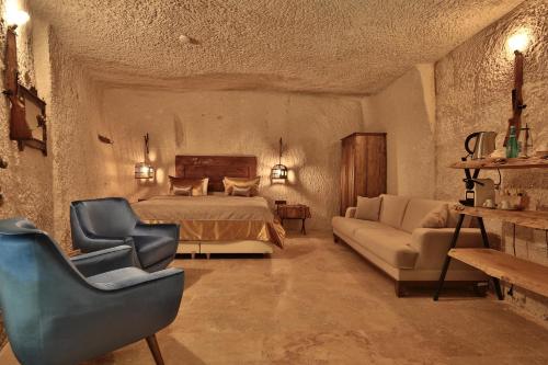 a bedroom with a bed and two chairs and a couch at The Owl Cave Hotel in Göreme