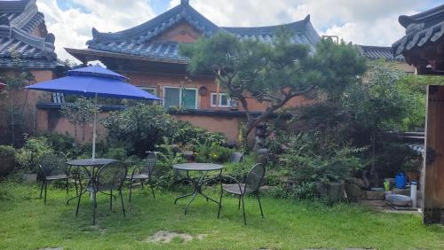 a table and chairs with an umbrella in a yard at Hanok Hyeyum in Jeonju