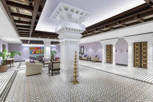 a lobby with a column and chairs and tables at Vivanta Ernakulam, Marine Drive in Cochin