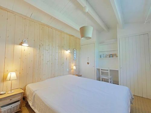 une chambre avec un lit blanc et des murs en bois dans l'établissement Maison de charme avec jardin clos, à 500 m du centre et 1800 m de la plage - 4 couchages - FR-1-224B-60, à Noirmoutier-en-l'lle