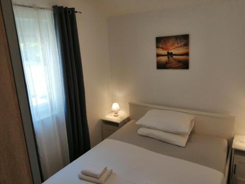 a bedroom with a white bed with a window at Apartmani Mila-Casa Bianca in Medulin