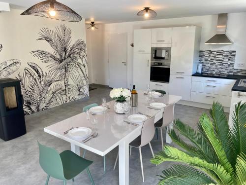 une salle à manger avec une table et des chaises blanches dans l'établissement Villa La Grée - 10 min à pied de la plage, à Sarzeau