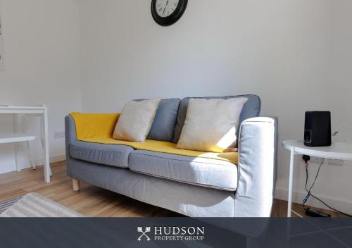 a couch in a living room with a clock on the wall at 1-Bedroom Apartment with Parking in Wellington