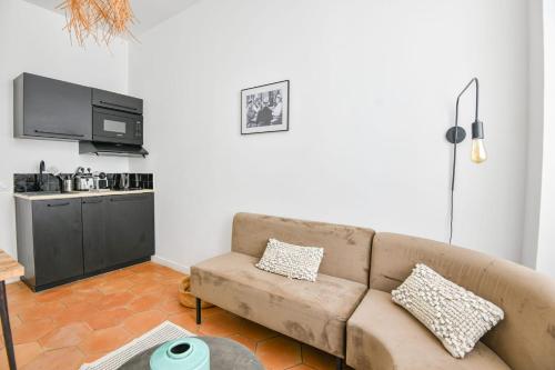 un salon avec un canapé et une cuisine dans l'établissement Chez Marius - Appart 1 ch avec clim - St Charles, à Marseille
