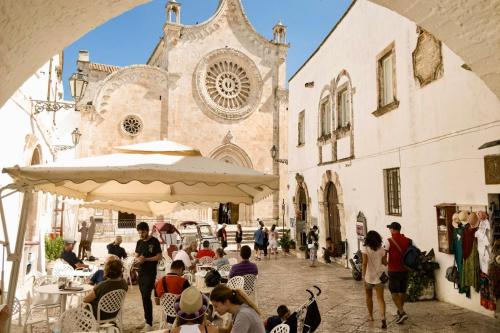 a group of people sitting at tables in front of a building at Iaru-Bed Experience House in Alberobello