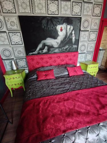a bedroom with a red bed with a painting on the wall at Le PALAZZO YES in Woël