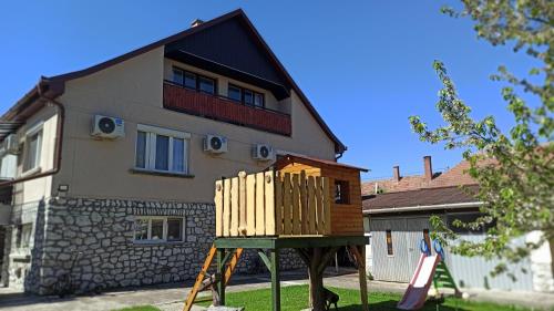 a wooden play structure in front of a house at La Siesta Bogács Apartman in Bogács