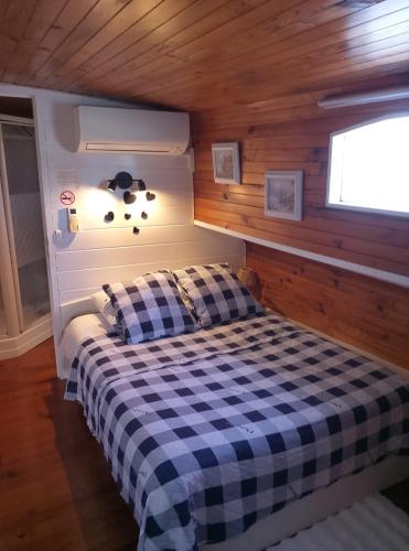 - une chambre avec un lit à damiers dans une cabine dans l'établissement PENICHE FARNIENTE CLIMATISEE - Aux Portes de la Camargue, à Bellegarde