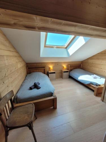 - une chambre mansardée avec 2 lits et une chaise dans l'établissement Chalet Le Grand Massif, à Les Villards-sur-Thônes