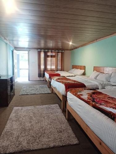 a group of four beds in a room at Hotel Narayana Palace in Harsil