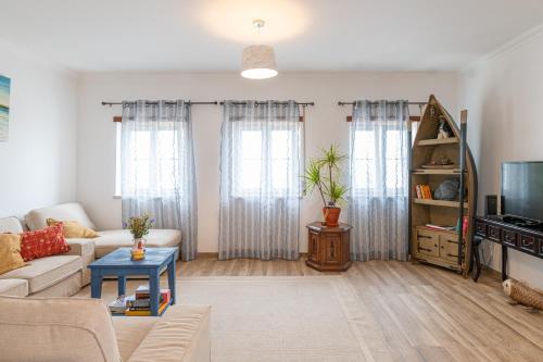 a living room with a couch and a tv at DONOTHING HOUSE - GUESTHOUSE - Baleal in Ferrel