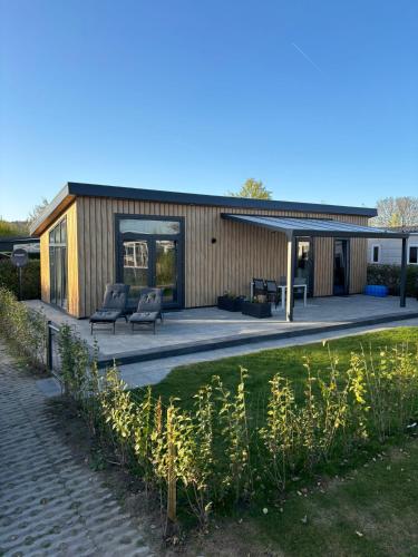 a house with two chairs and a patio at In Seenähe - Modernes Chalet im Ferienpark De Veerstal - familienfreundlich! in Lathum