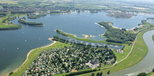 an aerial view of a lake with houses and trees at In Seenähe - Modernes Chalet im Ferienpark De Veerstal - familienfreundlich! in Lathum