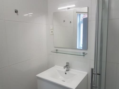 une salle de bain blanche avec un lavabo et un miroir dans l'établissement 1A studio à neuf Tout équipé, à Tourcoing