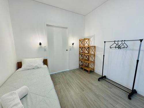 a white room with a bed and a closet at Albergue Pilares do Caminho in Marinhas