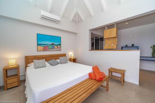 une chambre avec un lit blanc et un banc en bois dans l'établissement Villa Belharra Colombier St-Barths, à Saint Barthelemy