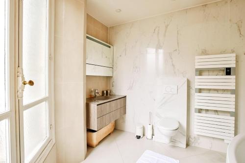 une salle de bain blanche avec des toilettes et un lavabo dans l'établissement Spacious flat - Champs Elysées, à Paris