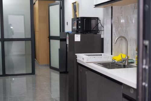 a kitchen with a sink and a stove and a microwave at Zuri Snug condo in Nairobi