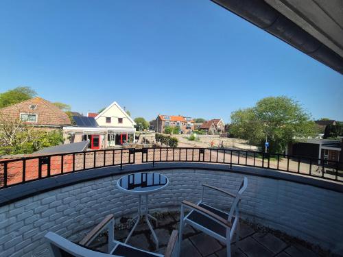 a patio with two chairs and a table and a fence at Hotel Den Burg in Den Burg