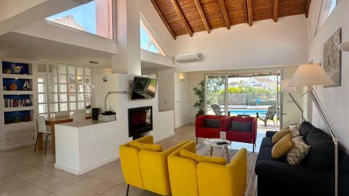 a living room with yellow chairs and a kitchen at Galo - Private Pool - 8 Guests - Albufeira in Albufeira