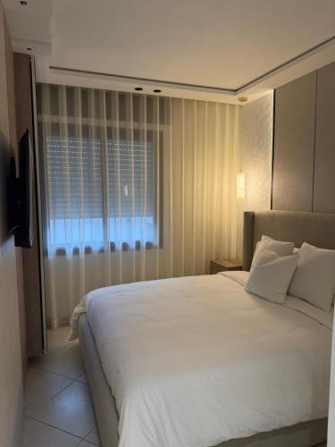 a bedroom with a large white bed and a window at Al amirat front sea only family in Martil