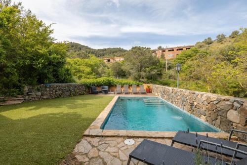 a swimming pool in a yard with a stone wall at Casa Argentera Full House in Argentera