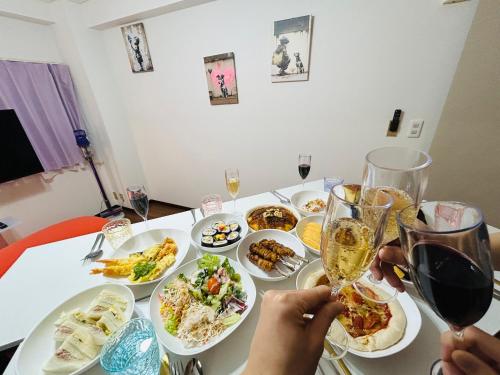 a table with plates of food and glasses of wine at 広島Riverside house第2ひまわり302号室 in Hiroshima