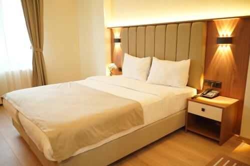 a bedroom with a large white bed with a telephone at Lioncity Hotel in Bursa