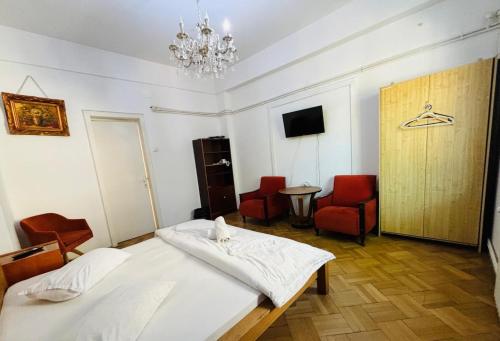 a bedroom with a bed and chairs and a chandelier at Iancu Apartments in Bucharest