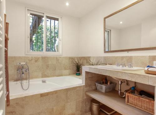 une salle de bain avec une baignoire, un lavabo et un miroir dans l'établissement Villa L'ile Bleue, à Ramatuelle