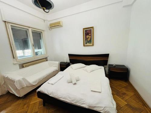 two beds in a room with white walls and wooden floors at Iancu Apartments in Bucharest