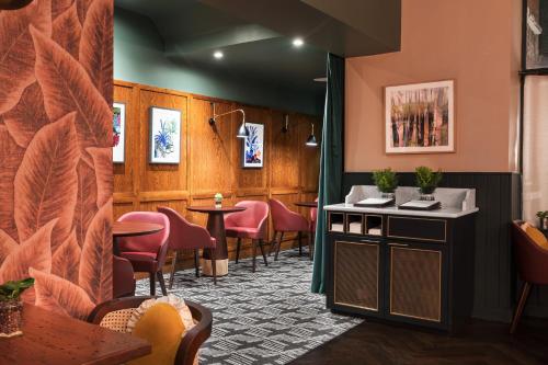 a waiting room with pink chairs and a table at Hotel Indigo London - Kensington by IHG in London