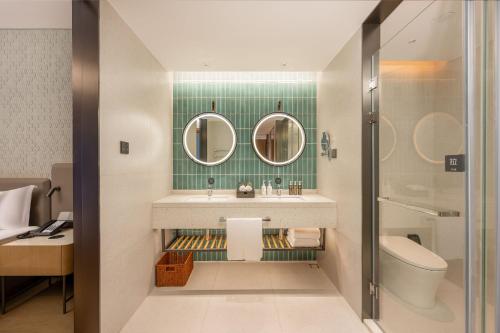 a bathroom with a sink and a toilet and mirrors at EVEN Hotel Quanzhou City Center by IHG in Quanzhou