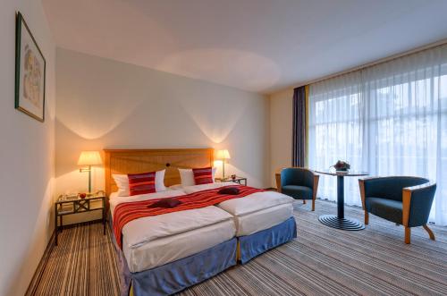 キュールングスボルンにあるHotel Aquamarinのベッド、テーブル、椅子が備わるホテルルームです。