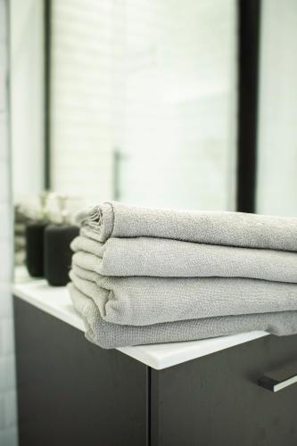 une pile de serviettes assises sur un comptoir dans la salle de bains dans l'établissement Le petit paddock, à Villeneuve-lès-Cerfs