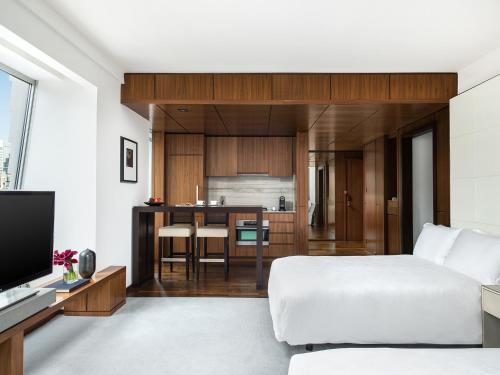 a bedroom with a white bed and a kitchen at The Langham, New York, Fifth Avenue in New York