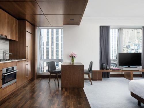 a living room with a table with chairs and a tv at The Langham, New York, Fifth Avenue in New York