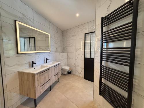 a bathroom with a sink and a mirror and a toilet at Villa Karasse in Lège-Cap-Ferret