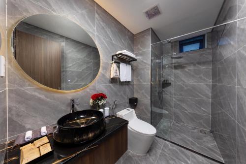 a bathroom with a sink and a toilet and a mirror at Cat Ba Wistaria Hotel- Jacuzzi Rooftop & Fitness in Cat Ba