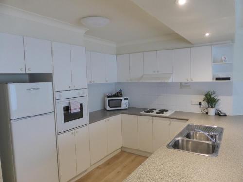uma cozinha branca com um lavatório e um frigorífico em Lifestyle Apartments at Ferntree em Fern Tree Gully