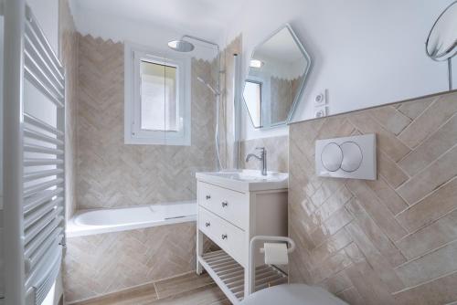 une salle de bain avec un lavabo, une baignoire et un miroir dans l'établissement Appartement T2 - Proche de la mer, à Fréjus
