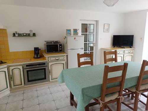 a kitchen with a table and a refrigerator at Belle maison familiale près de La Rochelle in Ferrières