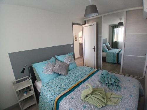 Schlafzimmer mit einem Bett mit blauer Bettwäsche und Kissen in der Unterkunft Petit Paradis aux Lones 2 min de la plage 3 chambres clim parking aperçu mer in Six-Fours-les-Plages