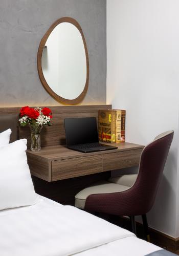 a bedroom with a desk with a laptop and a mirror at Cat Ba Wistaria Hotel- Jacuzzi Rooftop & Fitness in Cat Ba