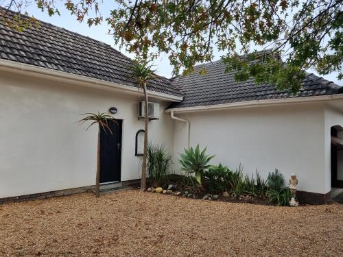 una casa blanca con una puerta negra y plantas en Somerset west Stay 1, en Somerset West